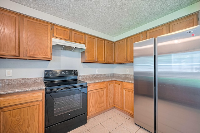 1806 Foxlake Dr, Houston, TX 77084 - kitchen with freestanding refrigerator, electric range, under cabinet range hood, light tile patterned floors, and light countertops