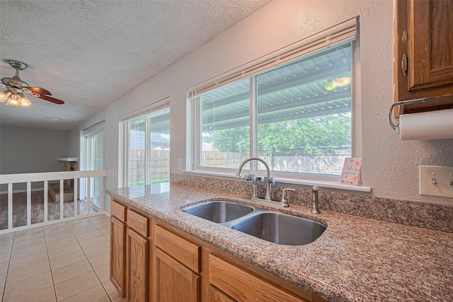 1806 Foxlake Dr, Houston, TX 77084 - kitchen featuring a sink, a textured ceiling, light tile patterned floors, ceiling fan, and light stone countertops