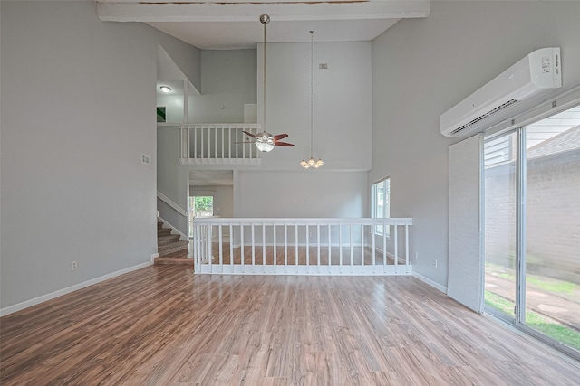 1806 Foxlake Dr, Houston, TX 77084 - empty room featuring a wall unit AC, wood finished floors, a ceiling fan, healthy amount of natural light, and a towering ceiling