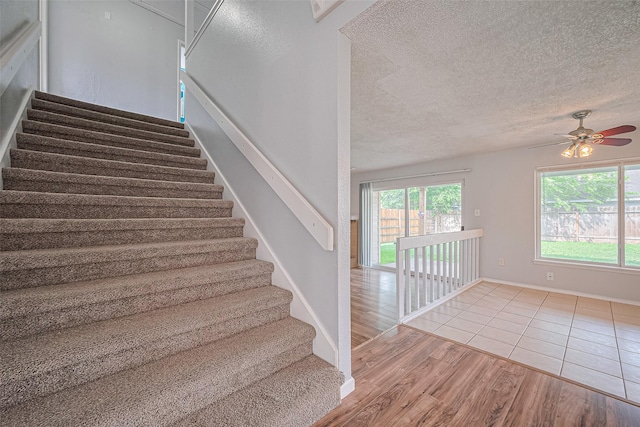 1806 Foxlake Dr, Houston, TX 77084 - stairway with wood finished floors, a ceiling fan, a textured ceiling, and baseboards