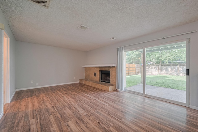 1806 Foxlake Dr, Houston, TX 77084 - unfurnished living room with wood finished floors, a textured ceiling, a brick fireplace, and baseboards