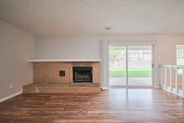1806 Foxlake Dr, Houston, TX 77084 - unfurnished living room featuring wood finished floors, healthy amount of natural light, a fireplace, and a textured ceiling