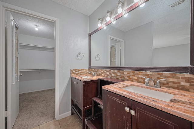 1806 Foxlake Dr, Houston, TX 77084 - full bath featuring a textured ceiling, backsplash, two vanities, a walk in closet, and tile patterned floors