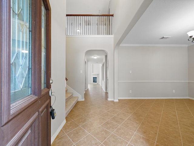 4015 Candle Cove Ct, Sugar Land, TX 77479 - entryway featuring light tile patterned floors, arched walkways, crown molding, stairs, and baseboards
