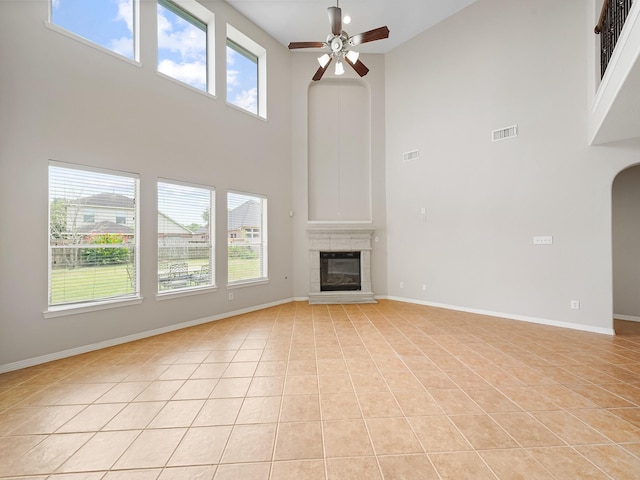 4015 Candle Cove Ct, Sugar Land, TX 77479 - unfurnished living room with a towering ceiling, a ceiling fan, light tile patterned flooring, baseboards, and a tiled fireplace