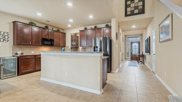 13822 Birney Point Ln, Houston, TX 77044 - kitchen featuring stainless steel fridge, black microwave, beverage cooler, backsplash, and light tile patterned flooring