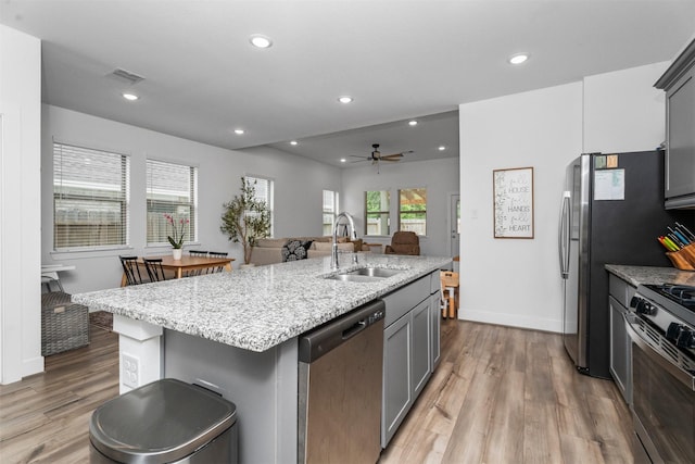 19180 Cedar Lennox Cir, Magnolia, TX 77355 - kitchen with stainless steel appliances, a sink, light wood-style floors, light stone countertops, and recessed lighting