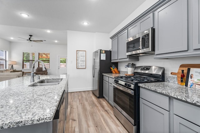 19180 Cedar Lennox Cir, Magnolia, TX 77355 - kitchen with stainless steel appliances, a sink, gray cabinetry, light wood finished floors, and recessed lighting