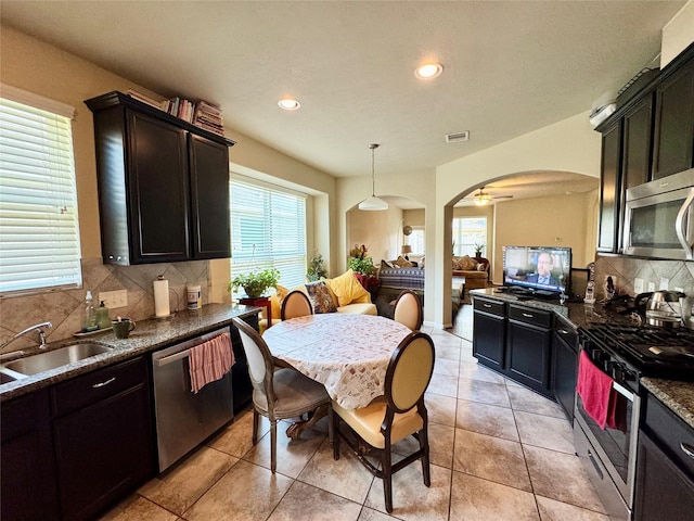 1315 Maple Ace Dr, Katy, TX 77493 - kitchen featuring stainless steel appliances, a sink, dark countertops, arched walkways, and recessed lighting