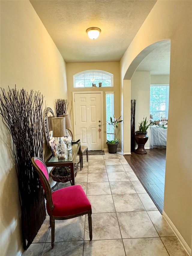 1315 Maple Ace Dr, Katy, TX 77493 - foyer entrance featuring a textured ceiling, arched walkways, light tile patterned floors, and baseboards