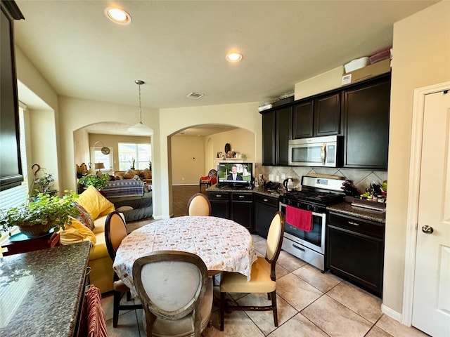 1315 Maple Ace Dr, Katy, TX 77493 - kitchen with stainless steel appliances, decorative backsplash, arched walkways, hanging light fixtures, and recessed lighting