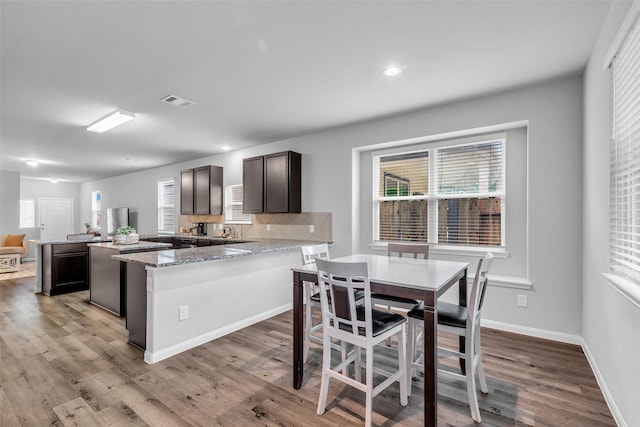 25424 Grotto Falls Ln, Porter, TX 77365 - kitchen with a kitchen island, light wood-style floors, tasteful backsplash, a peninsula, and dark brown cabinets