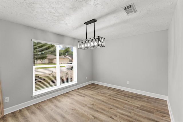 10503 Long River Dr, Sugar Land, TX 77498 - unfurnished dining area featuring a textured ceiling, a chandelier, wood finished floors, and baseboards