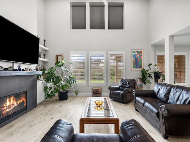 2965 Rustic Pier Ln, League City, TX 77573 - living room featuring a towering ceiling, a fireplace, light wood-type flooring, and baseboards