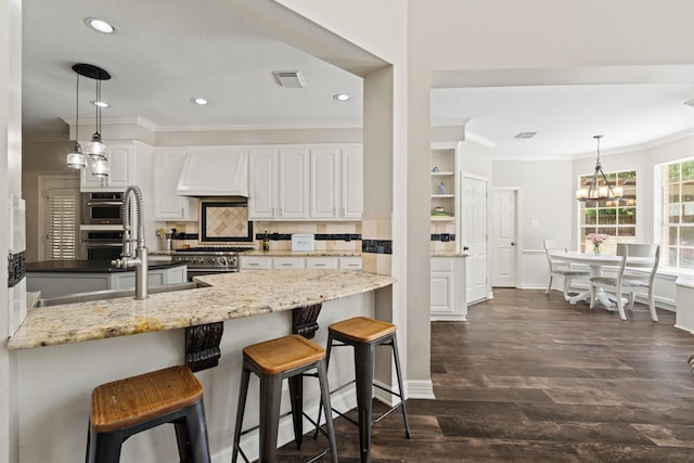 1915 Landon Point Cir, Katy, TX 77450 - kitchen featuring premium range hood, stainless steel appliances, ornamental molding, white cabinets, and dark wood finished floors