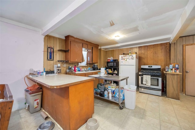 1806 State St, Houston, TX 77007 - kitchen with gas stove, freestanding refrigerator, black microwave, brown cabinetry, and a peninsula