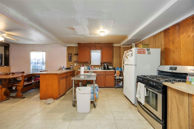 1806 State St, Houston, TX 77007 - kitchen with gas range, a peninsula, light countertops, brown cabinetry, and wooden walls