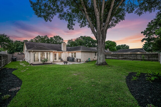907 Eva Dr, Katy, TX 77493 - back of property at dusk with a patio, a chimney, and brick siding