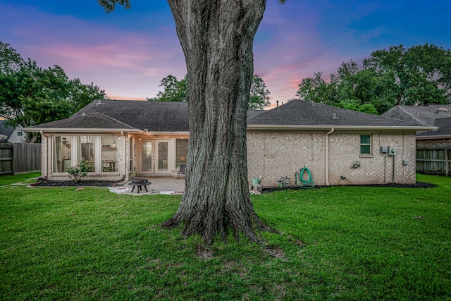 907 Eva Dr, Katy, TX 77493 - back of house at dusk featuring a patio, a sunroom, french doors, brick siding, and a shingled roof
