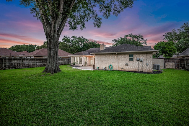 907 Eva Dr, Katy, TX 77493 - back of house at dusk with central AC unit, a patio, a chimney, and brick siding