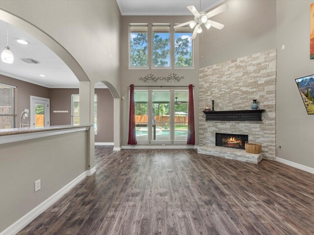 25169 Nutley Cir, Porter, TX 77365 - unfurnished living room featuring ceiling fan, crown molding, baseboards, a towering ceiling, and a stone fireplace