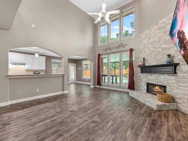 25169 Nutley Cir, Porter, TX 77365 - unfurnished living room with ceiling fan, dark wood-style flooring, a high ceiling, a fireplace, and baseboards