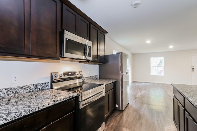 435 Connecticut St, Houston, TX 77029 - kitchen featuring stainless steel appliances, wood finished floors, dark brown cabinets, light stone counters, and recessed lighting