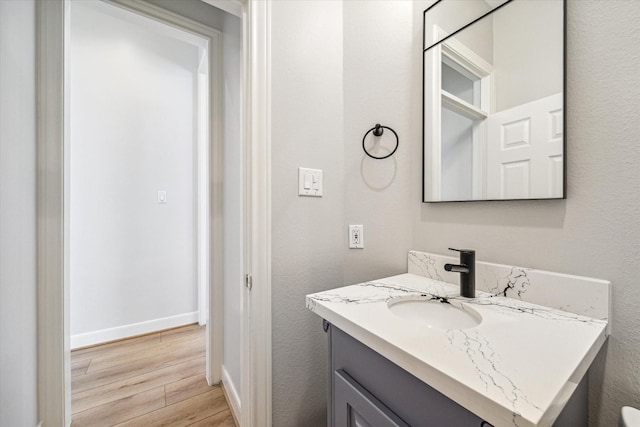 2215 Timbershade Ct, Magnolia, TX 77355 - bathroom with wood finished floors, vanity, baseboards, and a textured wall