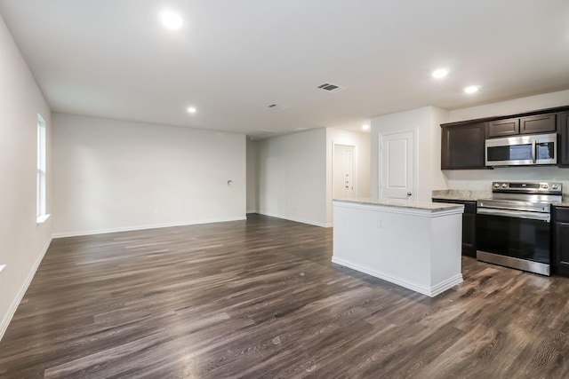9721 Stedman St, Houston, TX 77029 - kitchen with appliances with stainless steel finishes, a center island, open floor plan, dark wood-style floors, and recessed lighting