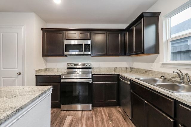 9721 Stedman St, Houston, TX 77029 - kitchen with appliances with stainless steel finishes, a sink, light wood-style floors, and dark brown cabinets