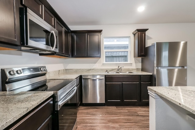 9721 Stedman St, Houston, TX 77029 - kitchen with appliances with stainless steel finishes, a sink, wood finished floors, light stone countertops, and dark brown cabinetry