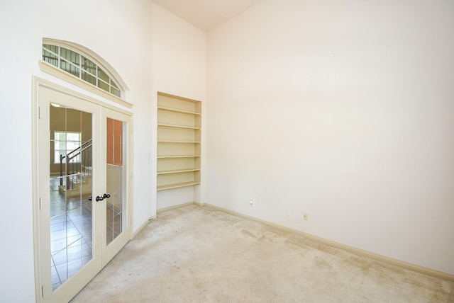 2614 Palm Harbour Dr, Missouri City, TX 77459 - carpeted empty room featuring french doors, baseboards, a high ceiling, and built in shelves