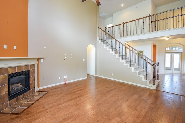 2614 Palm Harbour Dr, Missouri City, TX 77459 - unfurnished living room featuring a high ceiling, a tiled fireplace, wood finished floors, stairs, and baseboards