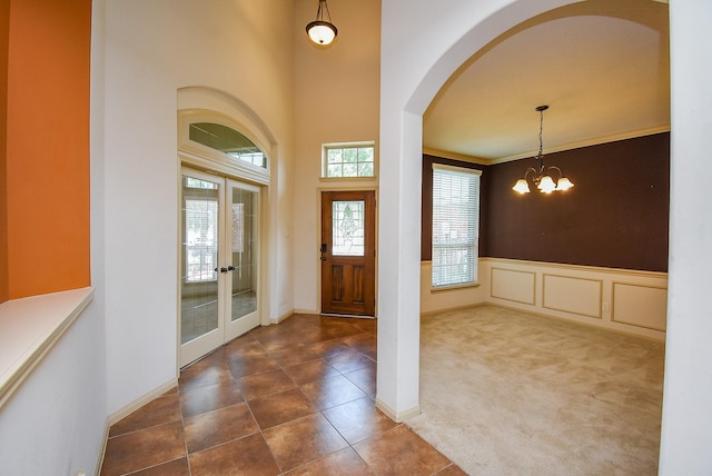 2614 Palm Harbour Dr, Missouri City, TX 77459 - carpeted foyer entrance with arched walkways, a wainscoted wall, a chandelier, french doors, and tile patterned floors