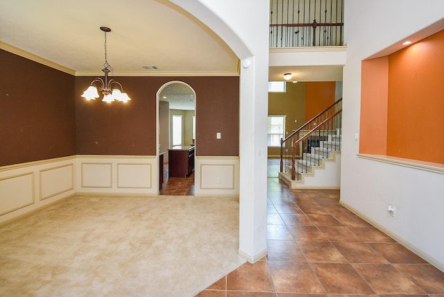 2614 Palm Harbour Dr, Missouri City, TX 77459 - empty room featuring arched walkways, a chandelier, ornamental molding, a wainscoted wall, and tile patterned flooring