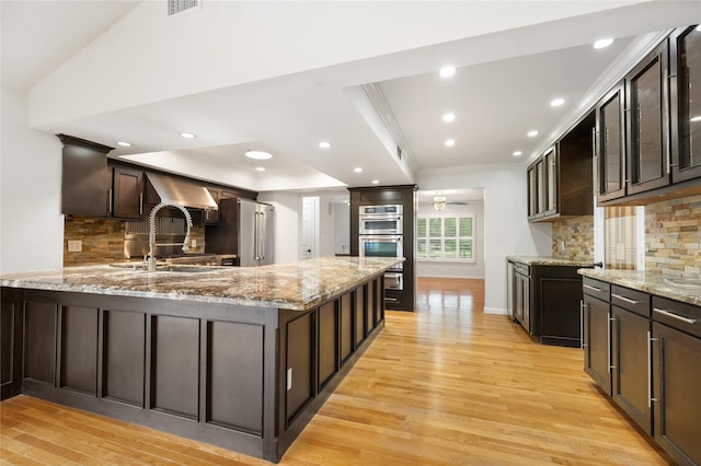 13 Whistlers Ct, The Woodlands, TX 77380 - kitchen featuring crown molding, light wood-style floors, stainless steel appliances, glass insert cabinets, and a peninsula