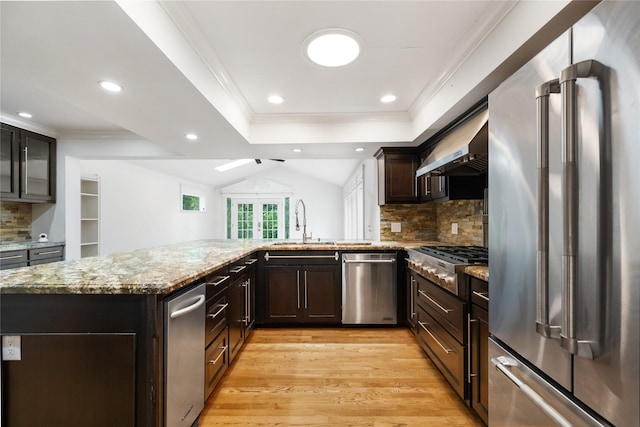 13 Whistlers Ct, The Woodlands, TX 77380 - kitchen featuring stainless steel appliances, light stone countertops, light wood-style floors, a sink, and tasteful backsplash