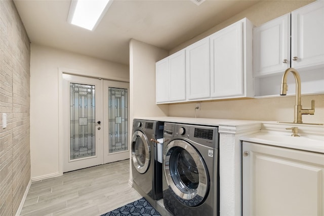 13 Whistlers Ct, The Woodlands, TX 77380 - washroom featuring washing machine and clothes dryer, cabinet space, light wood-style flooring, and brick wall