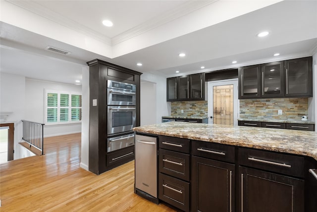 13 Whistlers Ct, The Woodlands, TX 77380 - kitchen featuring a warming drawer, double oven, ornamental molding, decorative backsplash, and light wood-type flooring