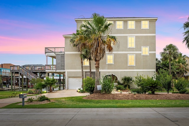 1854 Tiki Dr, Tiki Island, TX 77554 - view of front of house featuring an attached garage, a balcony, stucco siding, and concrete driveway