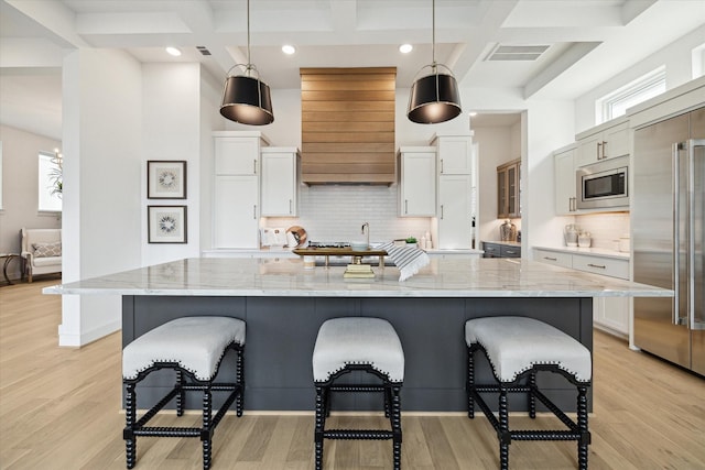 1115 Potomac Dr Unit B, Houston, TX 77057 - kitchen featuring coffered ceiling, built in appliances, a breakfast bar area, white cabinetry, and backsplash