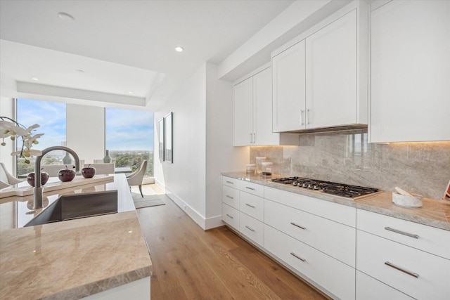 5656 San Felipe St Unit 1301, Houston, TX 77056 - kitchen with stainless steel gas stovetop, backsplash, light wood-style floors, white cabinets, and recessed lighting