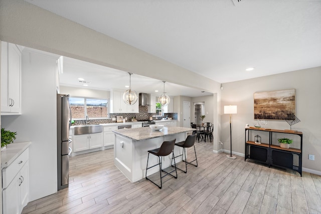 4003 Mischire Dr, Houston, TX 77025 - kitchen with appliances with stainless steel finishes, wall chimney range hood, a sink, light wood-style flooring, and a breakfast bar area