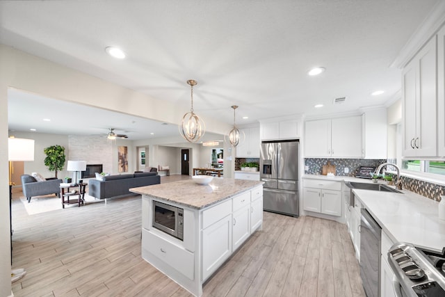 4003 Mischire Dr, Houston, TX 77025 - kitchen featuring appliances with stainless steel finishes, light wood-style flooring, a kitchen island, backsplash, and recessed lighting