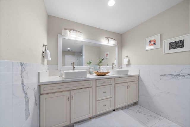 4003 Mischire Dr, Houston, TX 77025 - full bath with double vanity, marble look tiles, tile walls, and wainscoting