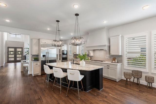 74 N Curly Willow Cir, Tomball, TX 77375 - kitchen with stainless steel appliances, plenty of natural light, custom range hood, an island with sink, and recessed lighting