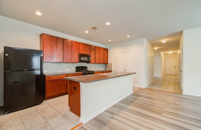 3102 Gianna Springs Ct, Humble, TX 77396 - kitchen featuring black appliances, backsplash, light wood-type flooring, an island with sink, and brown cabinets
