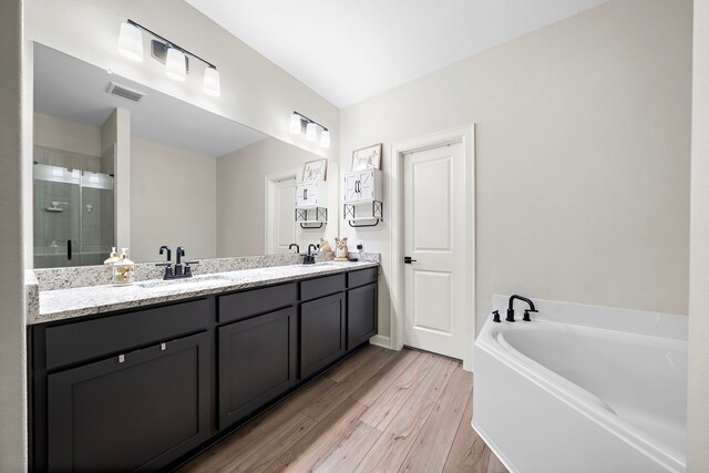 14122 Freeboard Dr, Santa Fe, TX 77510 - bathroom featuring wood finished floors, double vanity, a shower stall, and a garden tub
