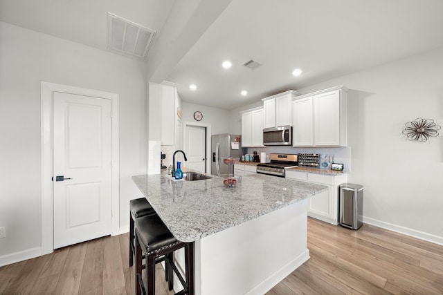 14122 Freeboard Dr, Santa Fe, TX 77510 - kitchen with appliances with stainless steel finishes, a sink, a kitchen breakfast bar, light wood-style floors, and recessed lighting