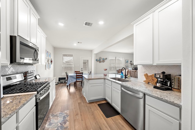 14122 Freeboard Dr, Santa Fe, TX 77510 - kitchen featuring stainless steel appliances, a sink, a peninsula, backsplash, and recessed lighting